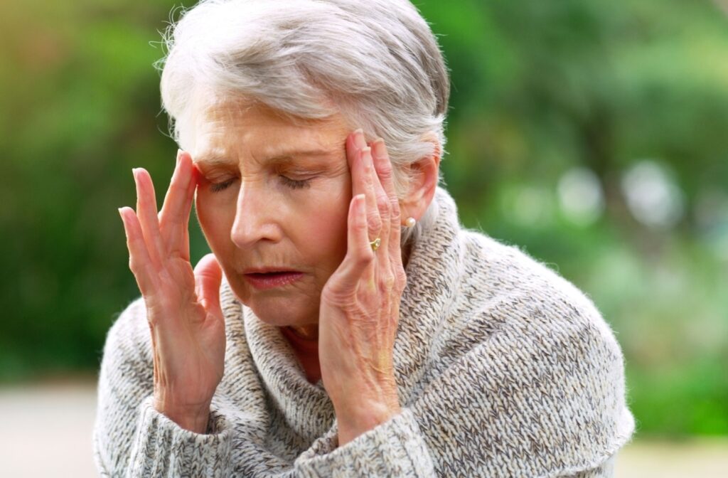 An older adult rubs their temples during a walk outside due to frustration from memory loss